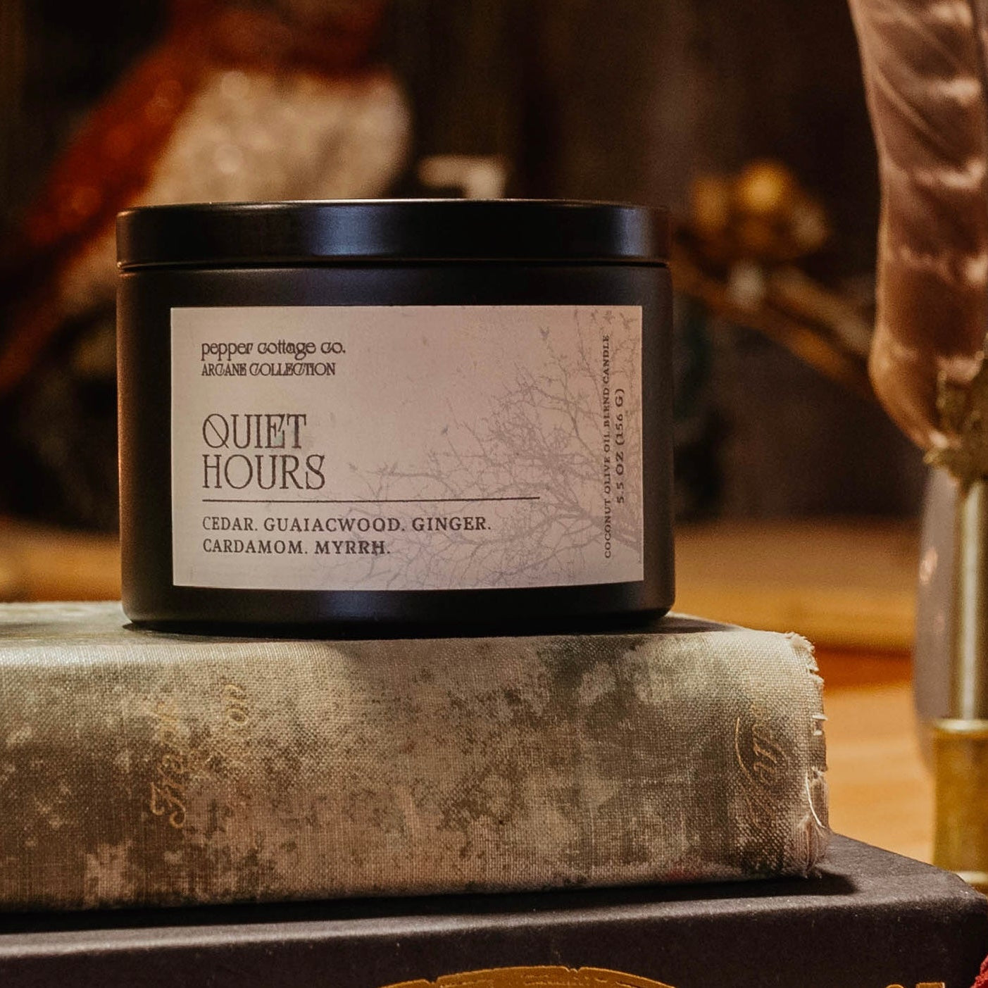 Candle labeled 'Quiet Hours' on a stack of books with a blurred background