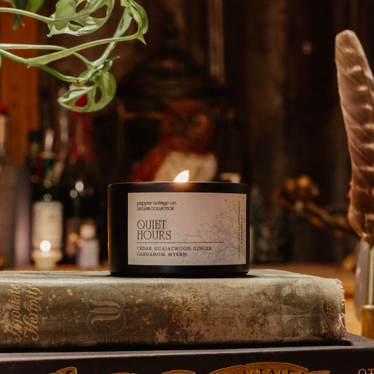 Candle labeled 'Quiet Hours' on a book with a blurred background