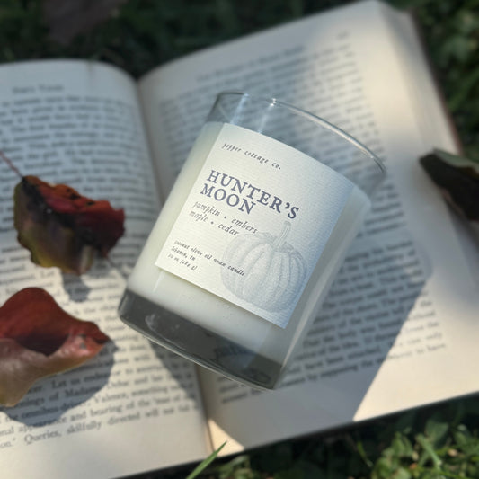 Candle labeled 'Hunter's Moon' on an open book outdoors